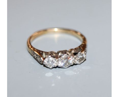 An 18ct and plat, three stone diamond ring, with diamond set shoulders, size M.