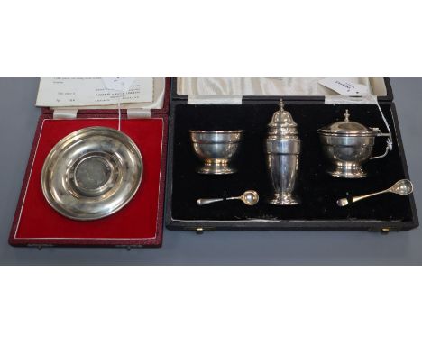A three-piece silver condiment set and a silver Churchill commemorative dish (both cased)