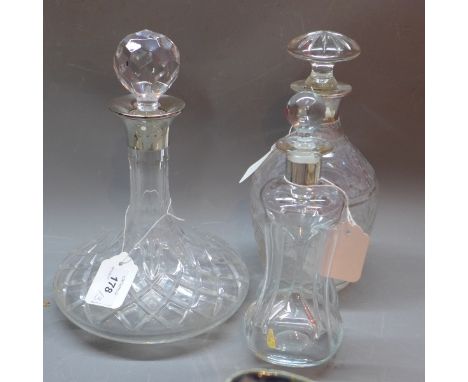 A silver topped decanter together with two others