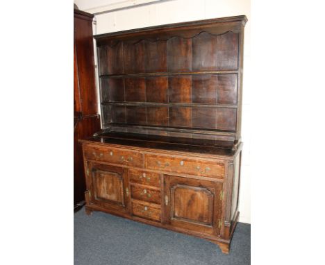 An 18th century oak dresser with two drawers above three central small drawers and two cupboards, with quarter column corners