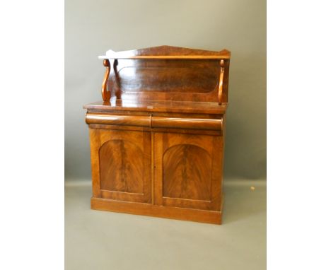 A Victorian mahogany chiffonier with a shaped drawer over two cupboards and upper section, with shelf supported on scroll end