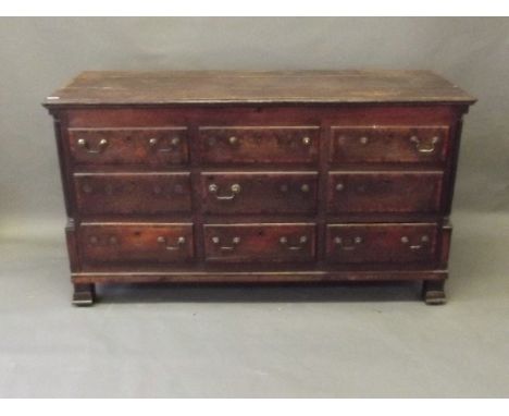 An C18th Lancashire oak mule chest with cross banded lift up top over six dummy and three true drawers, standing on tile feet