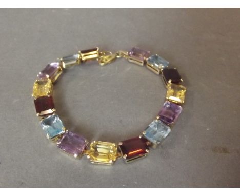 A gold 10ct bracelet set with garnet, citrine, aquamarine, and amethyst, 7'' long