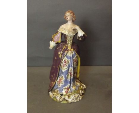 A C19th Continental porcelain figure of a lady wearing a long dress painted with flowers, standing on a gilt scrolled base, 9