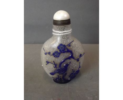 A Peking glass snuff bottle with bubbled glass and blue overlaid decoration of birds amongst cherry blossom, with Mother of P