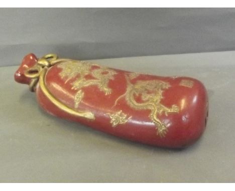 A Chinese red ground porcelain pillow in the form of a sack, with gilt relief decoration of dragons, impressed seal mark, 13'