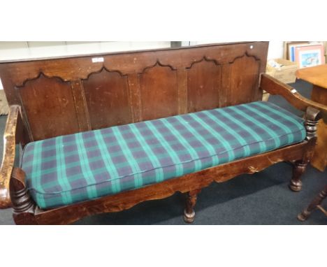 A large oak panelled hall bench resting on pad feet with upholstered cushion seating.