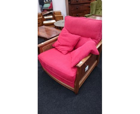 A large modern Ercol oak framed armchair with red fabric upholstered backrest, seat and cushions with Bergere style decorativ