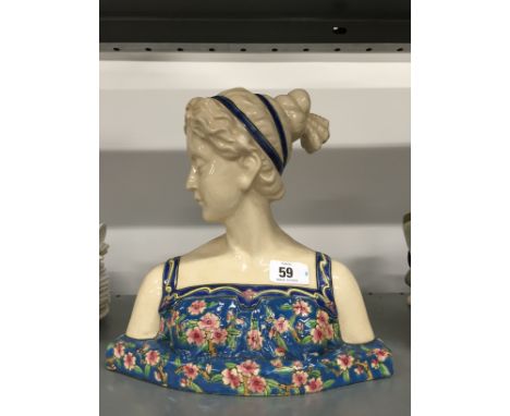 A Longwy style china bust modelled as a young girl wearing a floral strap dress.