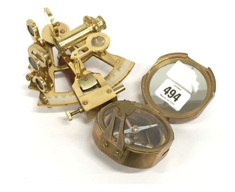 A reproduction folding brass compass together with a reproduction brass sextant.