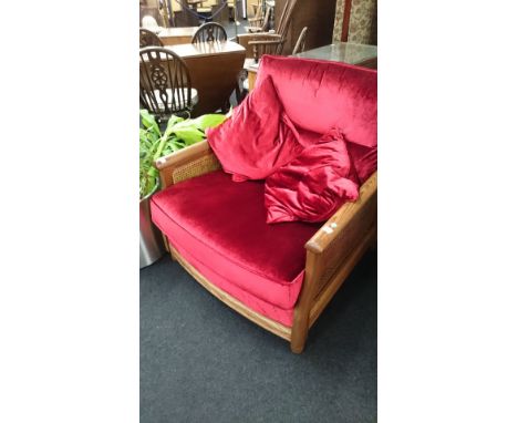 A large modern Ercol oak framed armchair with red fabric upholstered backrest, seat and cushions with Bergere style decorativ