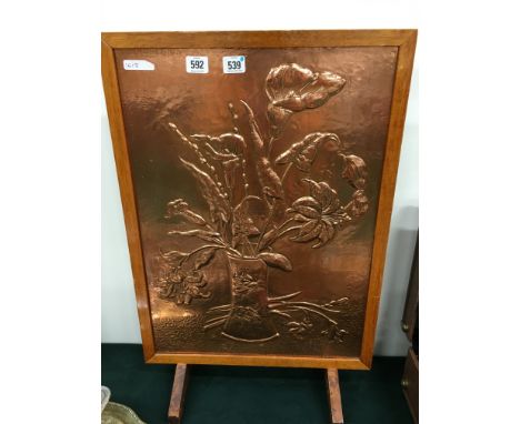 A copper fire screen: vase of lillies.