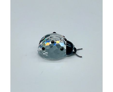 Clear body with black facets on back, black face with clear crystal eyes, metal antennae. Swarovski backstamp. This item has 