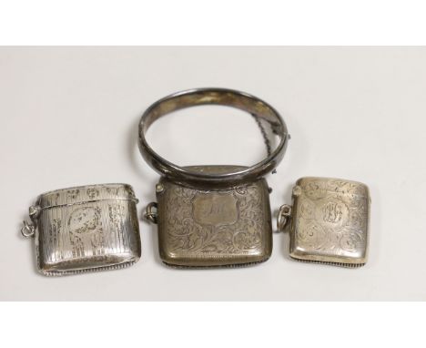 Three assorted late 19th/early 20th century chased silver vesta cases and a chased silver hinged bangle.