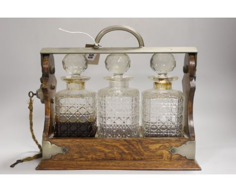 An oak three bottle tantalus, with key