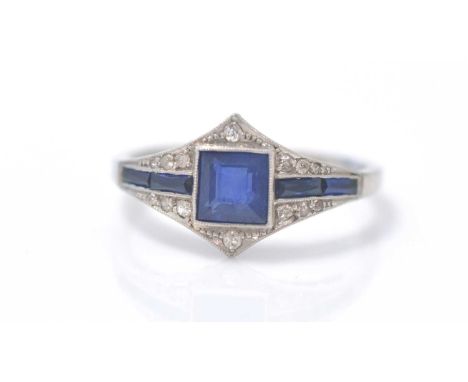 A sapphire and diamond dress ring, the square step-cut sapphire flanked by further sapphires in channel setting surrounded by