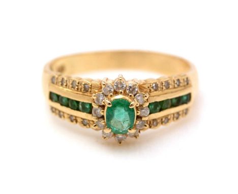 An emerald and diamond ring, the central emerald and diamond cluster flanked by emeralds in channel setting and further diamo