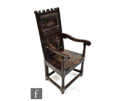 An oak wainscot chair in the 17th Century style, the fielded panel back above a solid seat and turned front legs, all above a