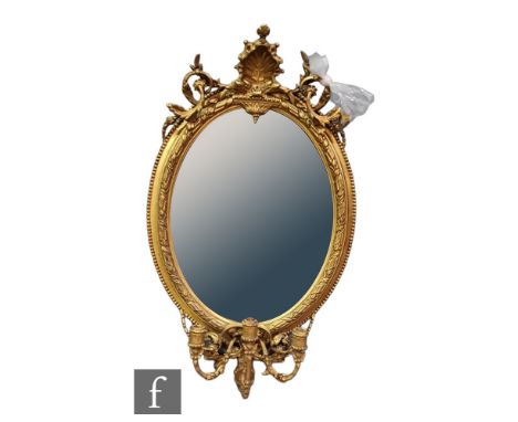 A late 19th to early 20th Century girandole wall mirror of oval form within a moulded gilt and gesso frame, with an acanthus 