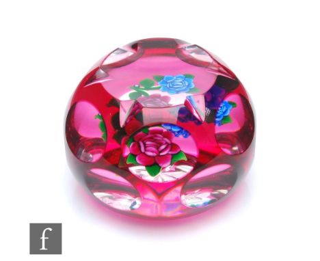 A John Deacons Magnum glass paperweight, internally decorated with blue and pink stylised flowers, cased in ruby with flash c