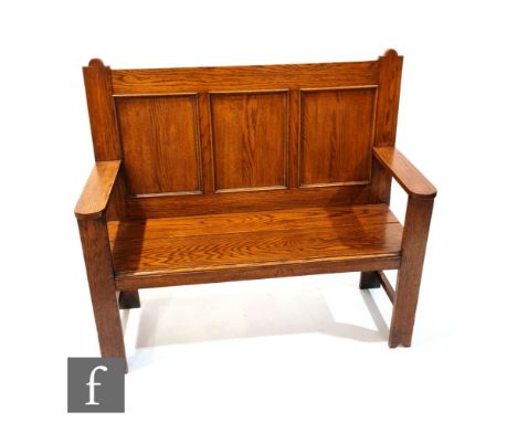 An early 20th Century oak two seat settle, with triple fielded panel back over the solid seat, height 111cm, width 122cm and 