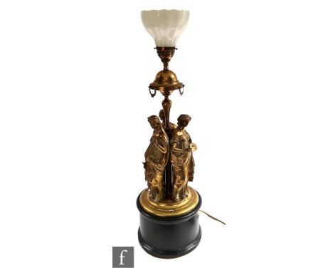 An early 20th Century brass lamp in the Grand Tour style depicting the three graces below a Vaseline shade, on circular eboni