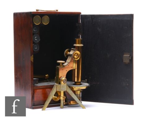 An early 20th Century brass microscope in wooden case, unnamed, on tripod stand, with spare lenses and accessories and lens s