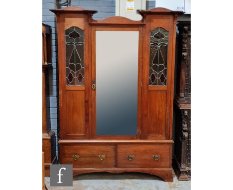 A Scottish Arts and Crafts mahogany wardrobe, the architectural pediment above a central door with bevelled mirror panel, fla