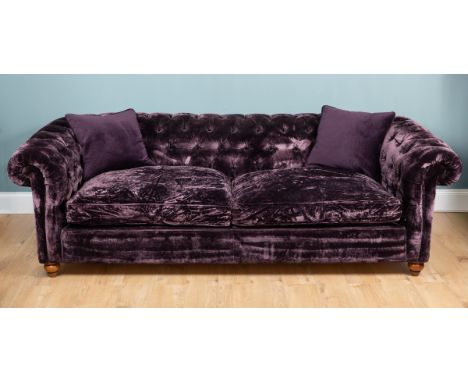 A large purple velvet button-upholstered Chesterfield sofa With scrolling button upholstered arms and back, all raised on tur