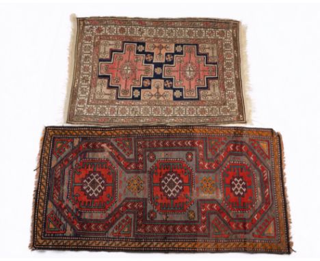 Two early 20th century rugs The first an Oushak rug with two central medallions on a blue ground with a guarded border; the s