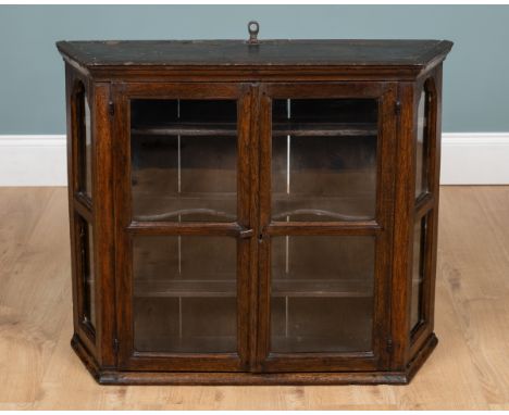 An 18th century Dutch oak wall cabinet  With twin glazed doors enclosing shaped shelves and with old iron suspension hook to 