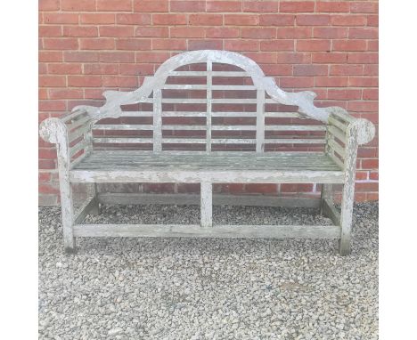 A Lutyens-style teak garden bench The camel-back and the seat with slats enclosed by scrolling arms.166cm wide x 62cm deep x 
