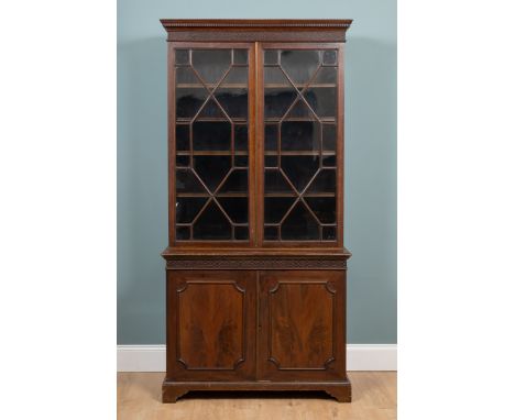 A late 19th century astragal glazed bookcase With a blind fret carved cornice above glazed doors enclosing four adjustable sh