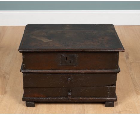 An 18th century oak chest With a hinged lid caught by a leather strap, above two drawers with turned handles, and raised on c