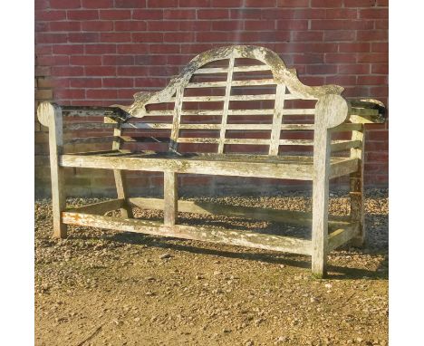 A Lutyens-style teak garden bench The camel-back and the seat with slats enclosed by scrolling arms.166cm x 102cmQty: 1Weathe