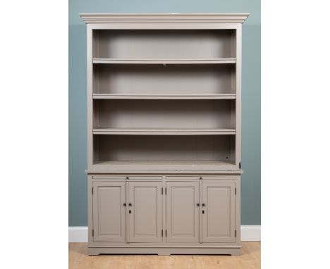 A grey-painted bookcase The top with three open shelves on a base with two slides above twin panelled cupboard doors opening 