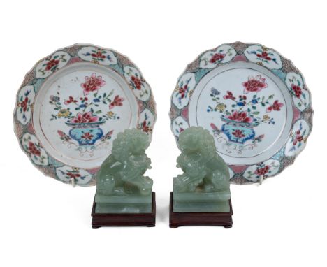 A pair of Chinese dogs of fo and a pair of famille rose porcelain plates The dogs of fo of jade and standing on wooden bases,