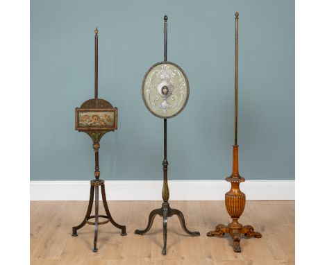 Two 19th century pole screens and a further pole screen stand The first with a painted screen depicting cherubs on a splayed 