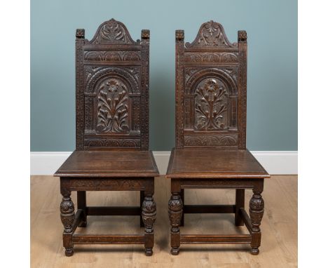 A pair of Victorian, Gothic Revival, carved oak hall chairs The relief carved back and plank seats raised on cup and cover ca