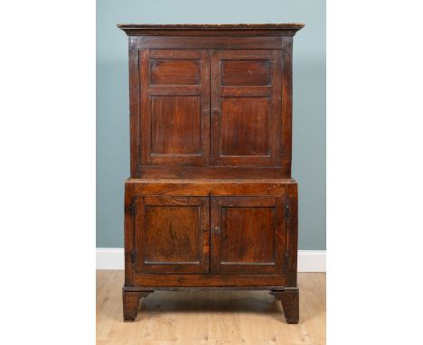 An 18th century oak cupboard The top with twin panelled doors opening to reveal later added shelves within, raised on a base 