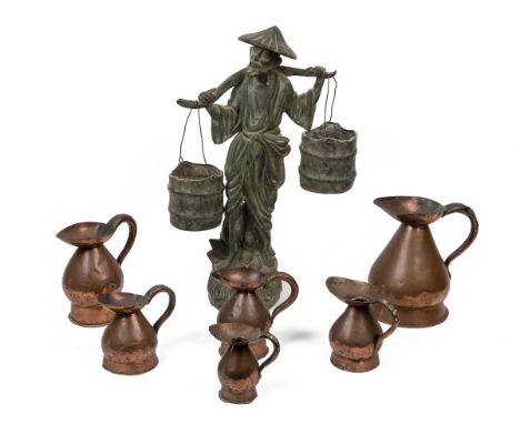 A 20th century bronze statue and six measuring jugs Depicting a man carrying a pair of buckets by a yoke, on a circular base;