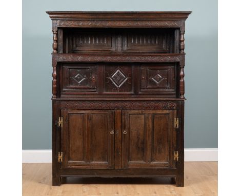 An 18th century oak tridarn with chip-carved decoration The top above twin-panelled doors raised on a base with twin-panelled