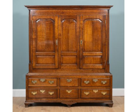 A Georgian oak linen press The two-panelled cupboard doors opening to reveal hanging space with a rail and hooks, raised on a