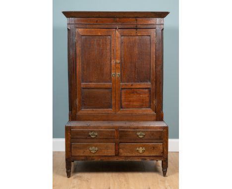 A 19th century oak linen press With twin-panelled doors above two dummy drawers and two fitted drawers, standing on tapered f