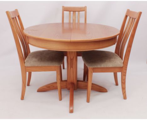 A small light oak circular extending dining table with three chairs - late 20th century, the pull-out top with single flip-up