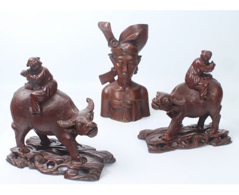 A pair of Chinese carved and lacquered hardwood figures of figures riding water buffalo - early 20th century, with inset glas