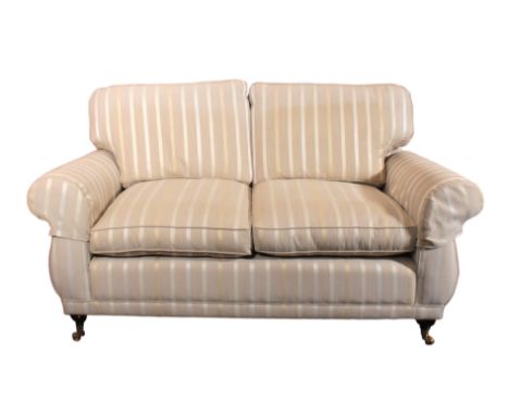 A Laura Ashley two-seater sofa - beige, silver and gold striped upholstery, the ebonised front feet on brass castors, (LWH 17