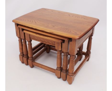A nest of three mid-elm tables by Ercol - maker's label beneath top of the largest table, the rounded rectangular tops on tur