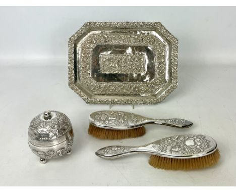 An Indian white metal three piece dressing table set - comprising a covered globular box, on three ball feet and two brushes,