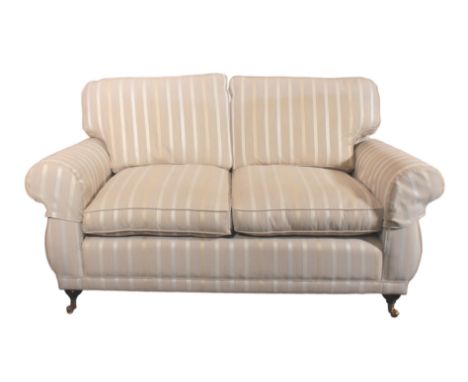 A Laura Ashley two-seater sofa - beige, silver and gold striped upholstery, the ebonised front feet on brass castors, (LWH 17